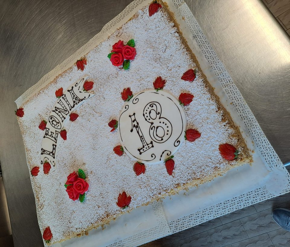 Eighteenth birthday cake with icing sugar, strawberries and red roses