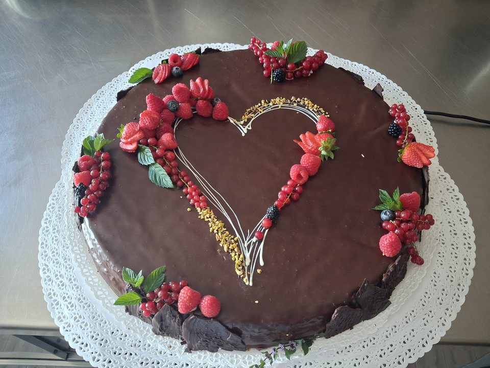 Chocolate cake with a decorative heart, strawberries and mixed berries
