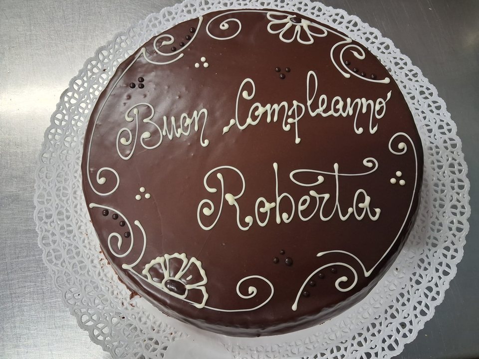 Chocolate-glazed birthday cake with light-coloured lettering and decorations