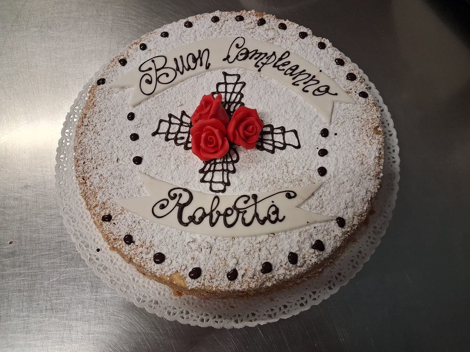 Birthday cake with icing sugar, red roses and chocolate decorations