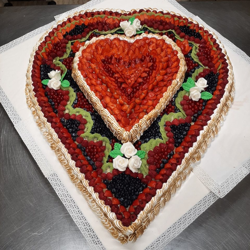 Double-heart cake with strawberries, kiwi, mixed berries and white roses